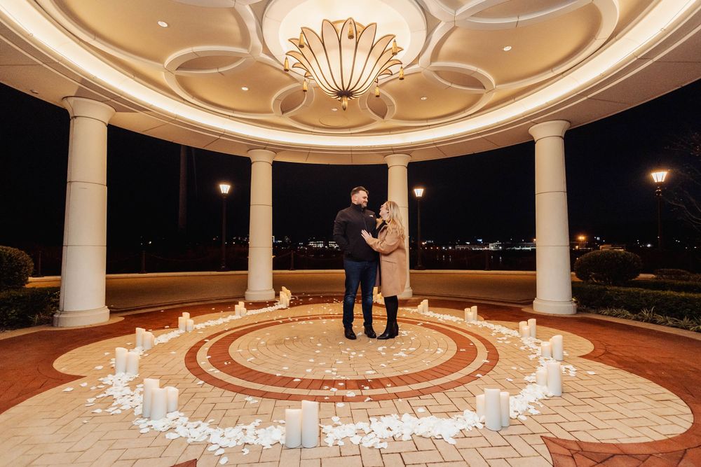 An elegant gazebo proposal scene with white candles arranged in a circular pattern on the floor.