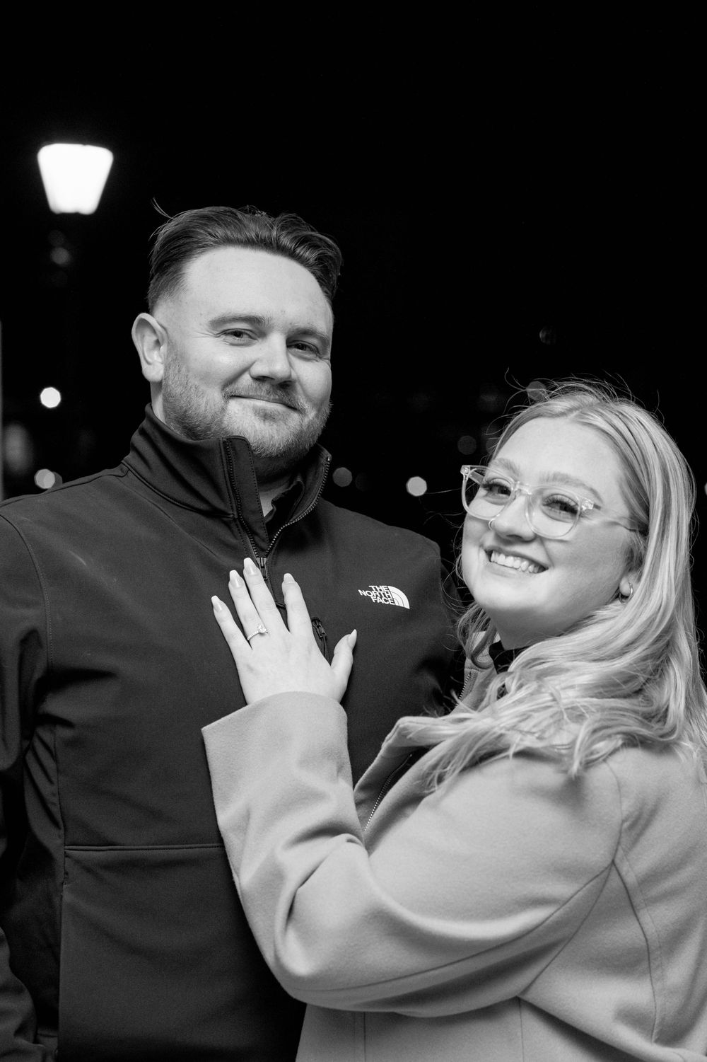 A black and white engagement portrait showing joy and excitement.