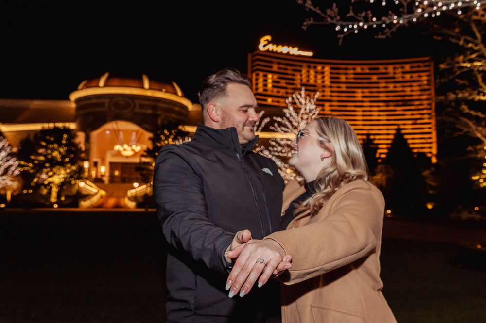 Couple embracing at night with Las Vegas casino lights in the background.