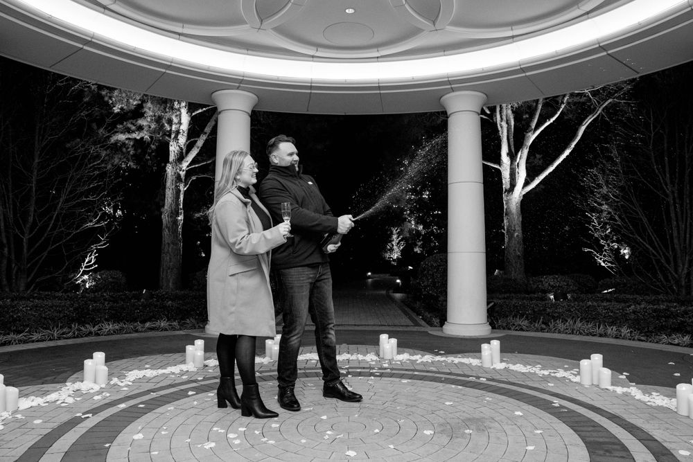 A black and white photo of two people celebrating in a candle-lit circular gazebo.