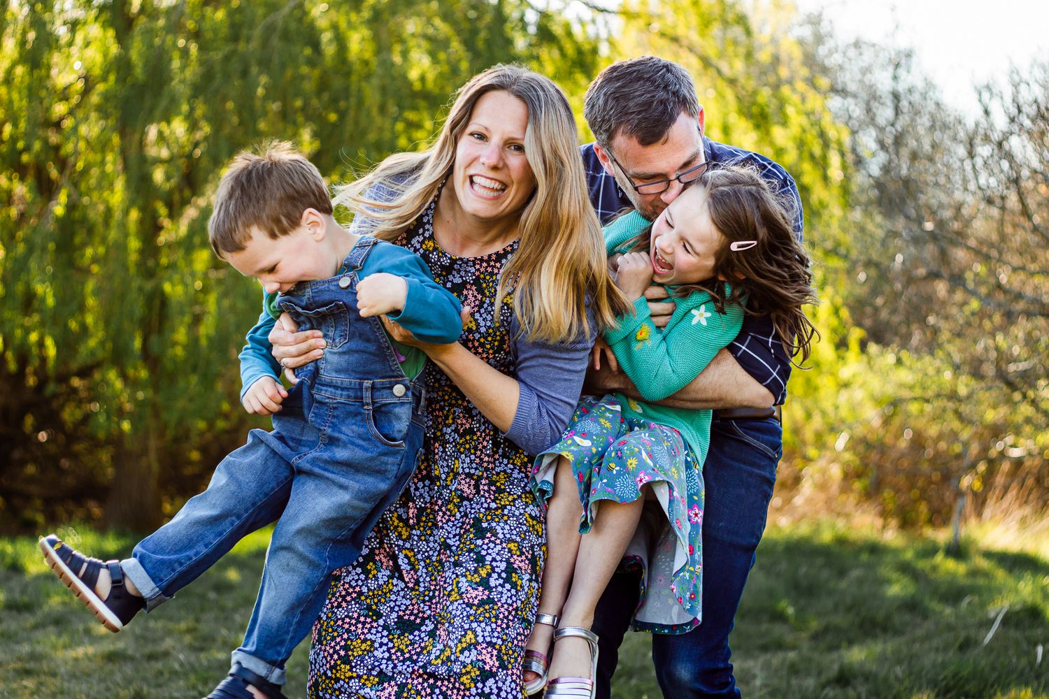 In a field in Havant, Hampshire, a fun family of four hug, play and laugh under a willow tree.