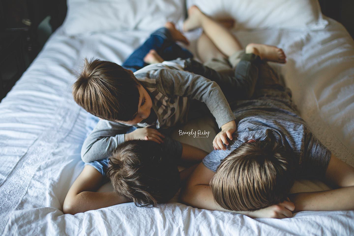 brothers playing on parent's bed with a white comforter