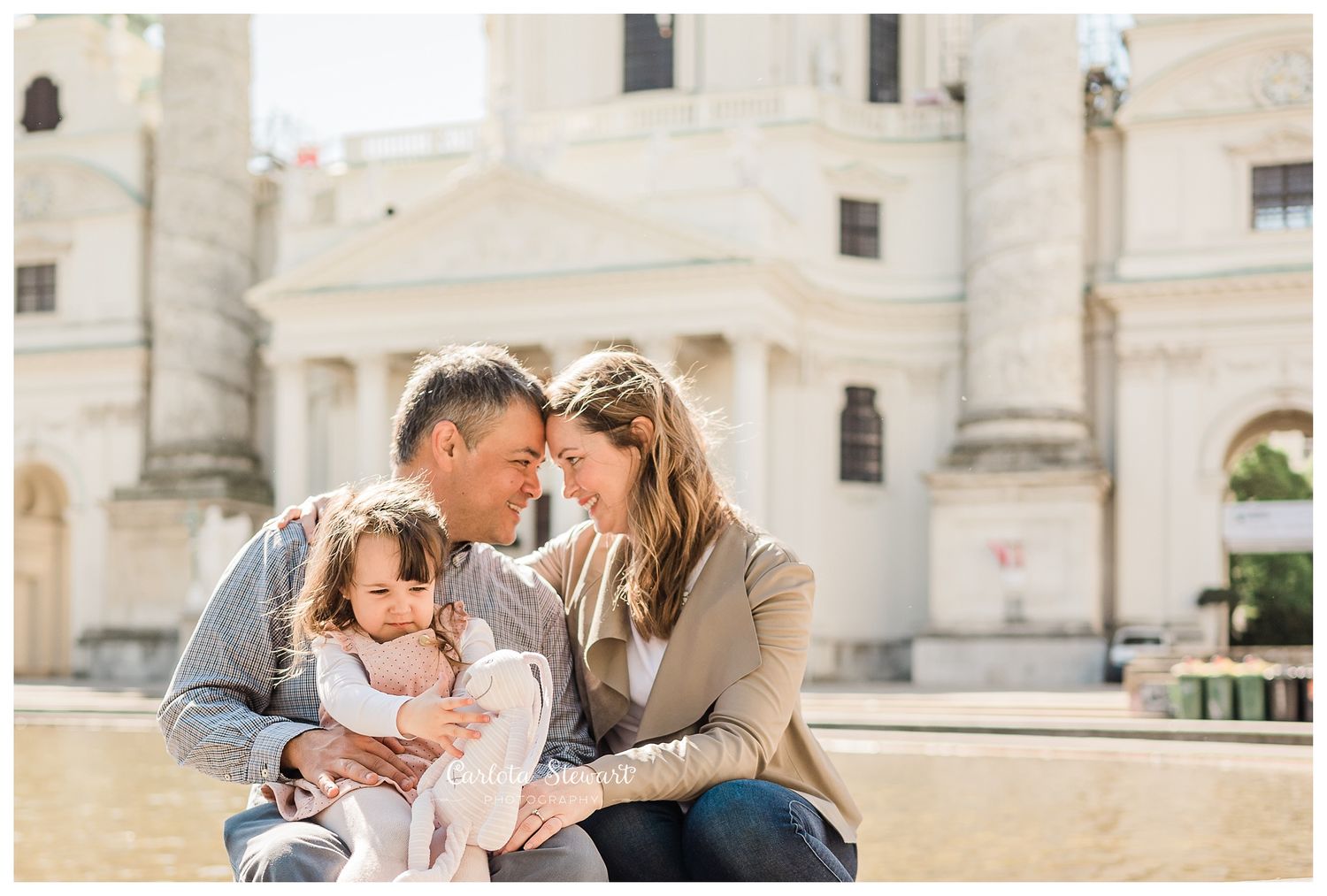Family of three posing for a photograph in front of Charles Church in Vienna in Spring
