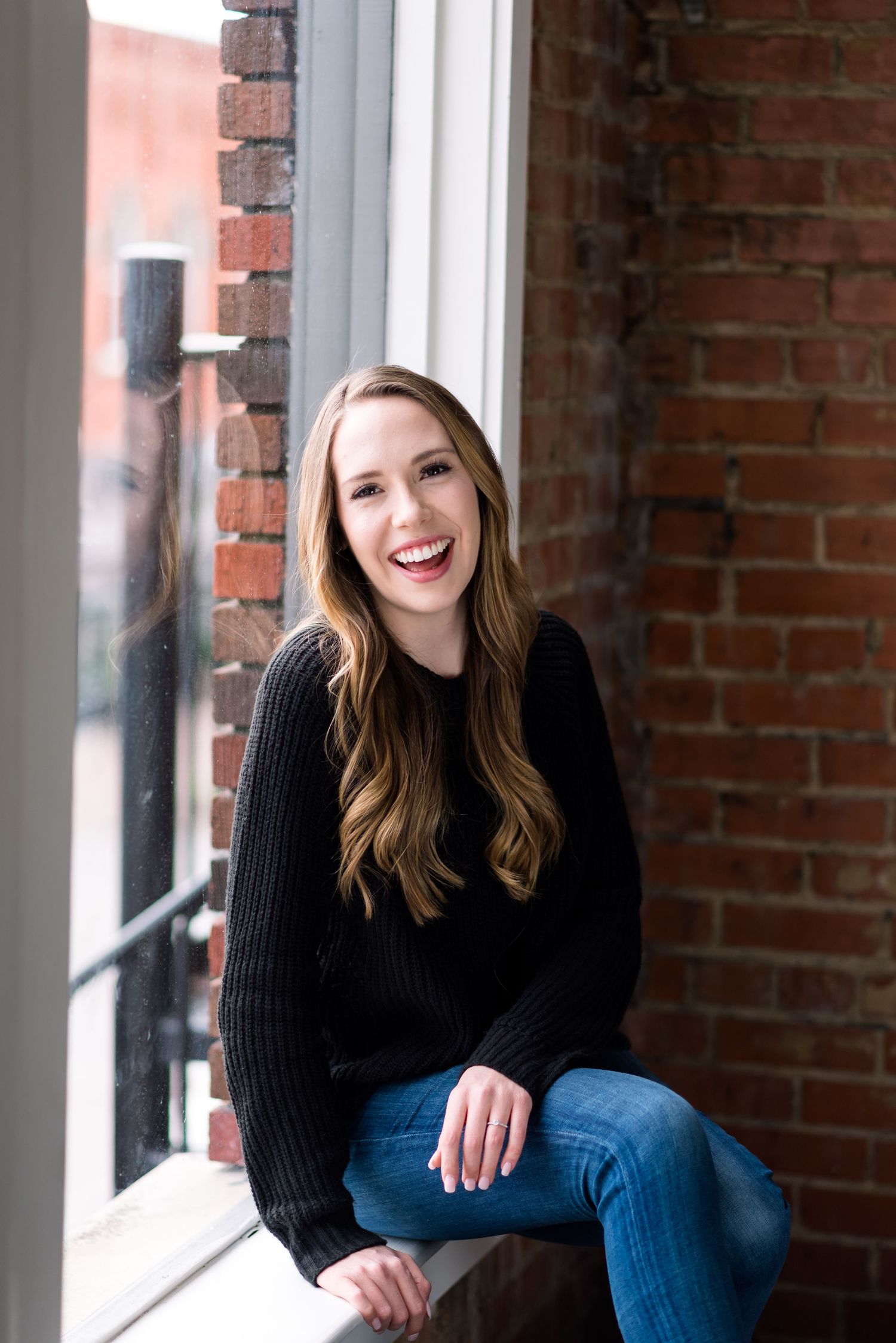 Mordi Photographie laughs near a window at a studio in McKinney Texas.