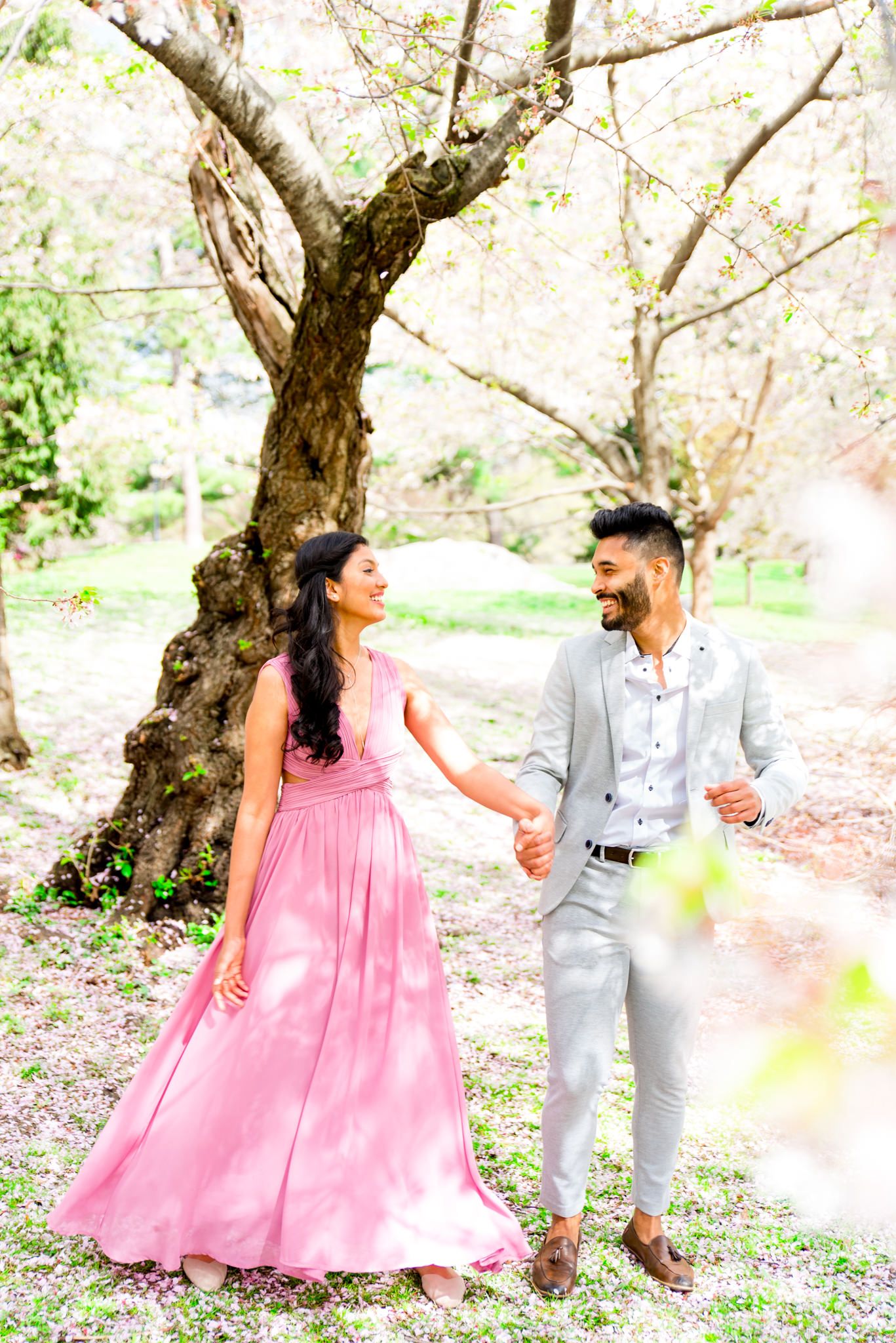 young couple holding hands under the cherry blossoms in Central Park engagement photos
