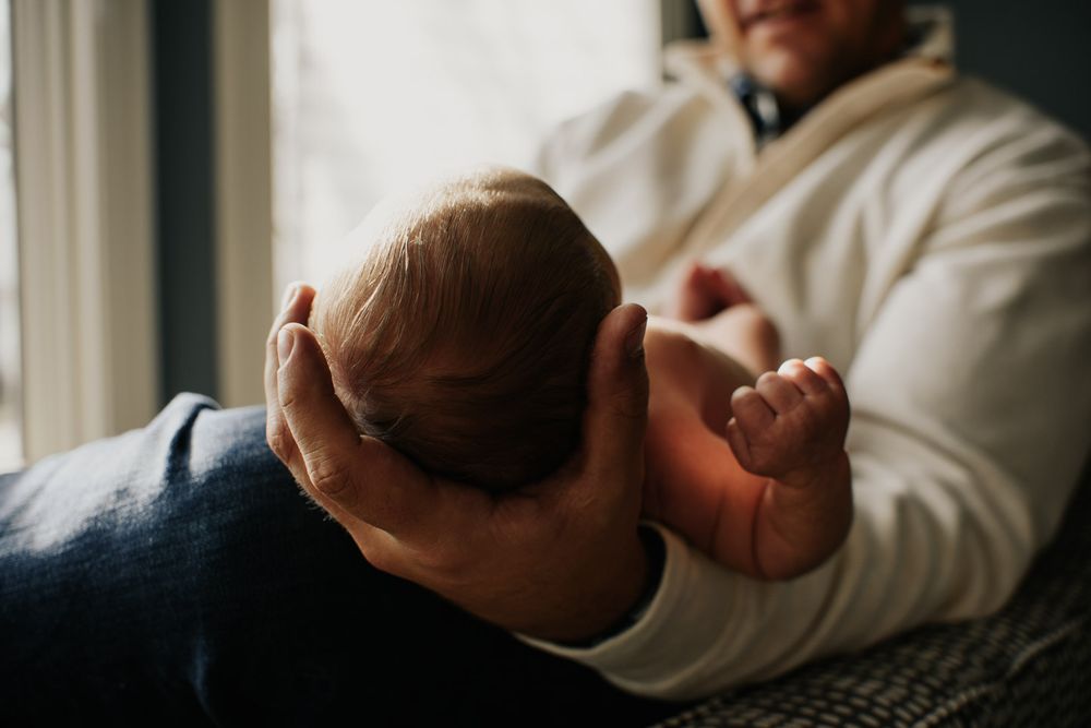 Vanourny Newborn Session Lifestyle Photography Kansas City Close up of newborn baby boys head cradled in father's hand