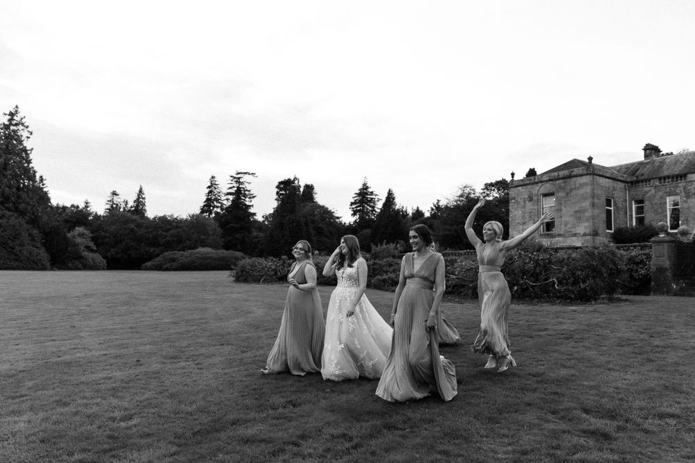 bride and her bridesmaids playing around in the gourds off a stately home