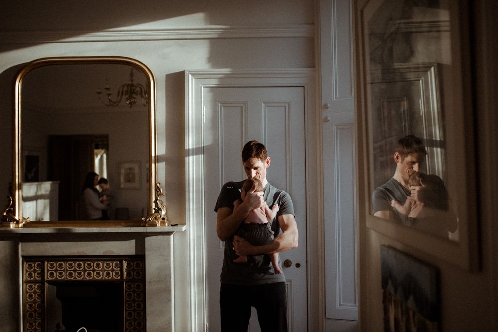 father holding his son in front of large mirror