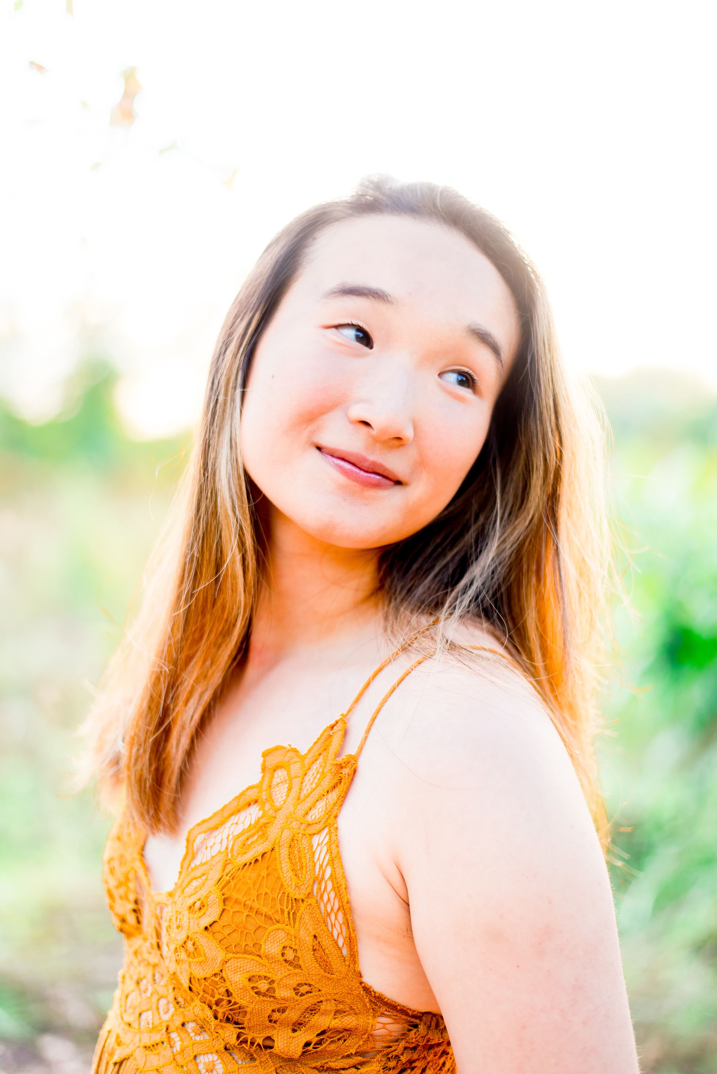 high school senior girl in yellow lace dress smiling and looking to the side