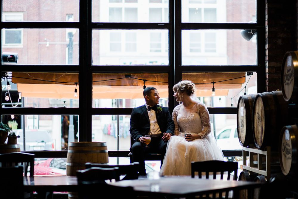 Bride and groom sitting in the window of a brewery by Hudson Valley photographer
