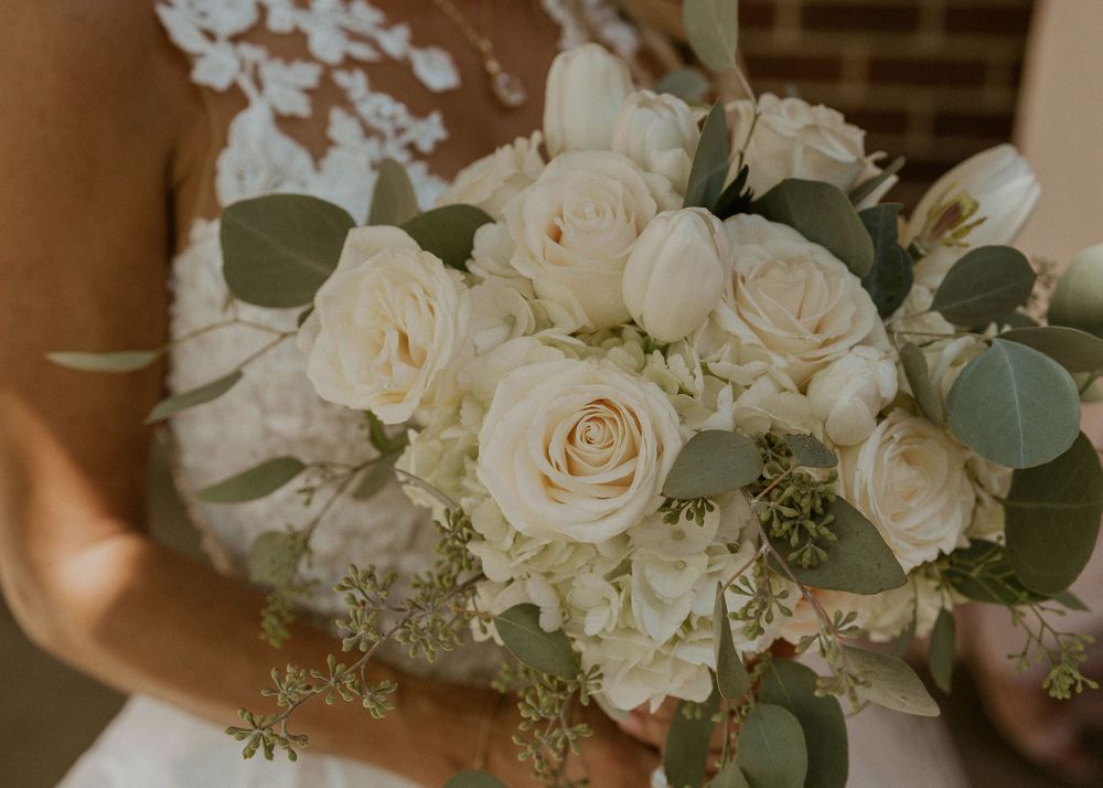 Bride carries her bouquet of white and blush roses and hydrangeas
