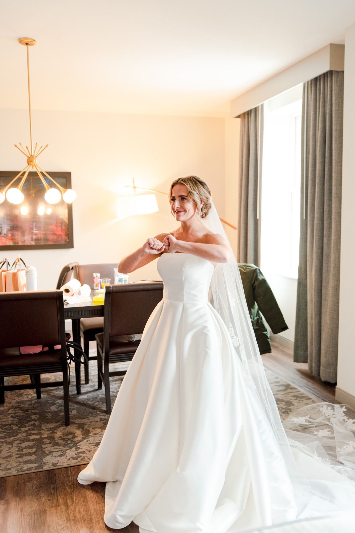 blonde bride dancing in hotel room after the first look with her bridesmaids