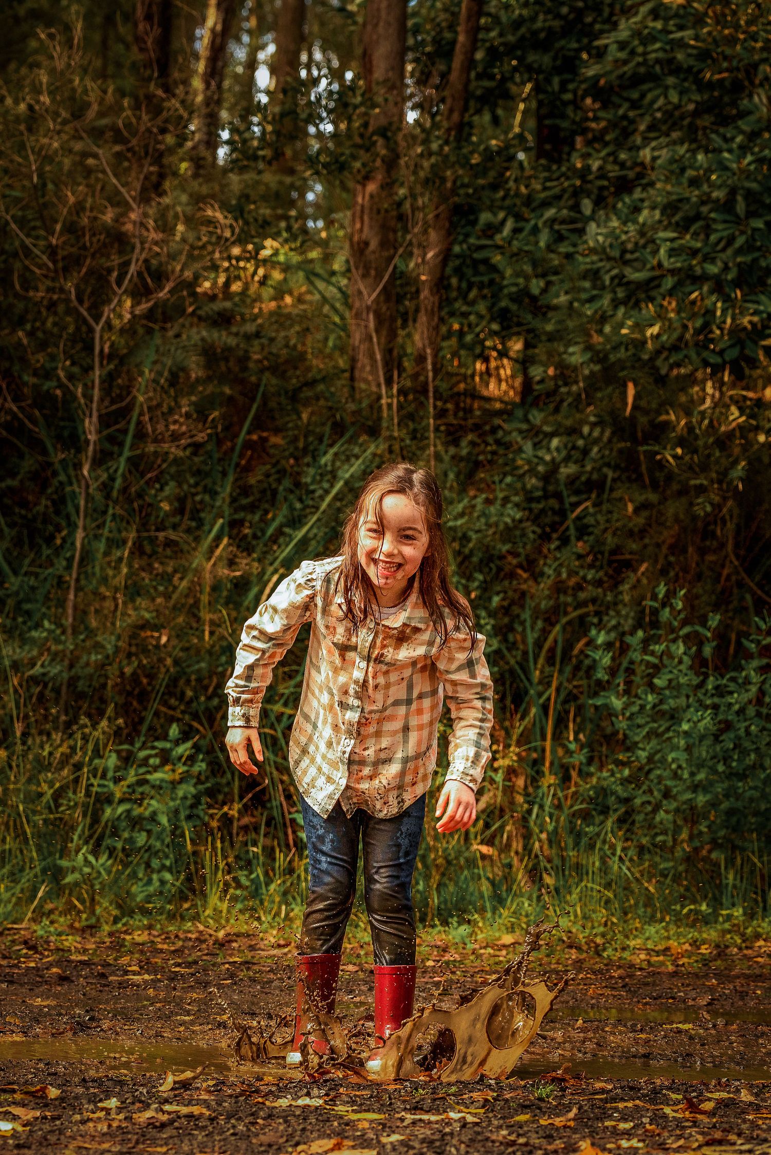 Young child jumping in mud