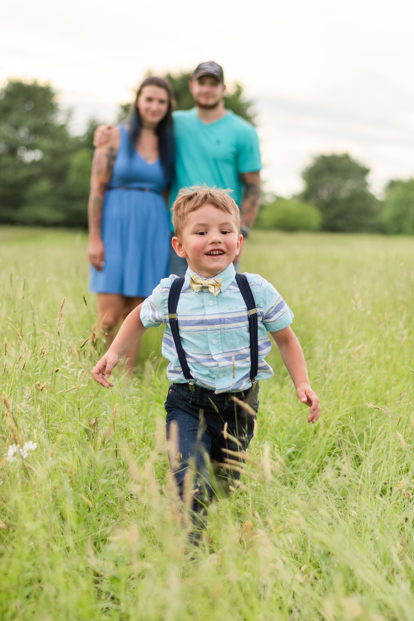 Little boy running through field and parents standing in background in Clarion Pennsylvania