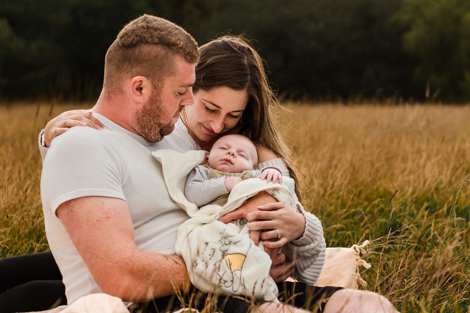 In a field in Havant new parents sit in the long grass snuggling their newborn baby boy.