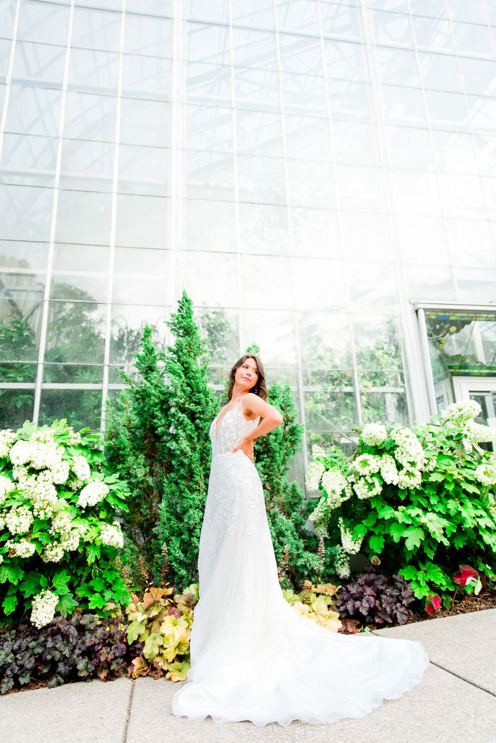 dark haired bride in KF Serafina Gown stands with hands on hips at Krohn Conservatory wedding