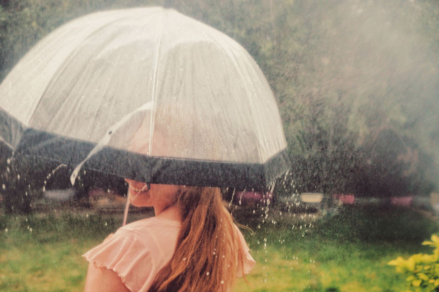 A girl spins and laughs under her umbrella in the rain.