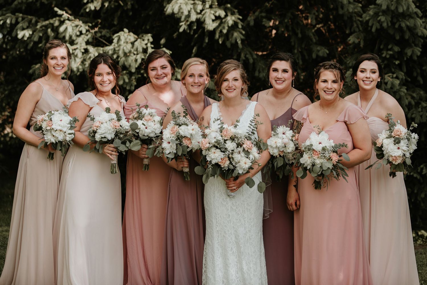 bridesmaids standing with bride in the middle smiling