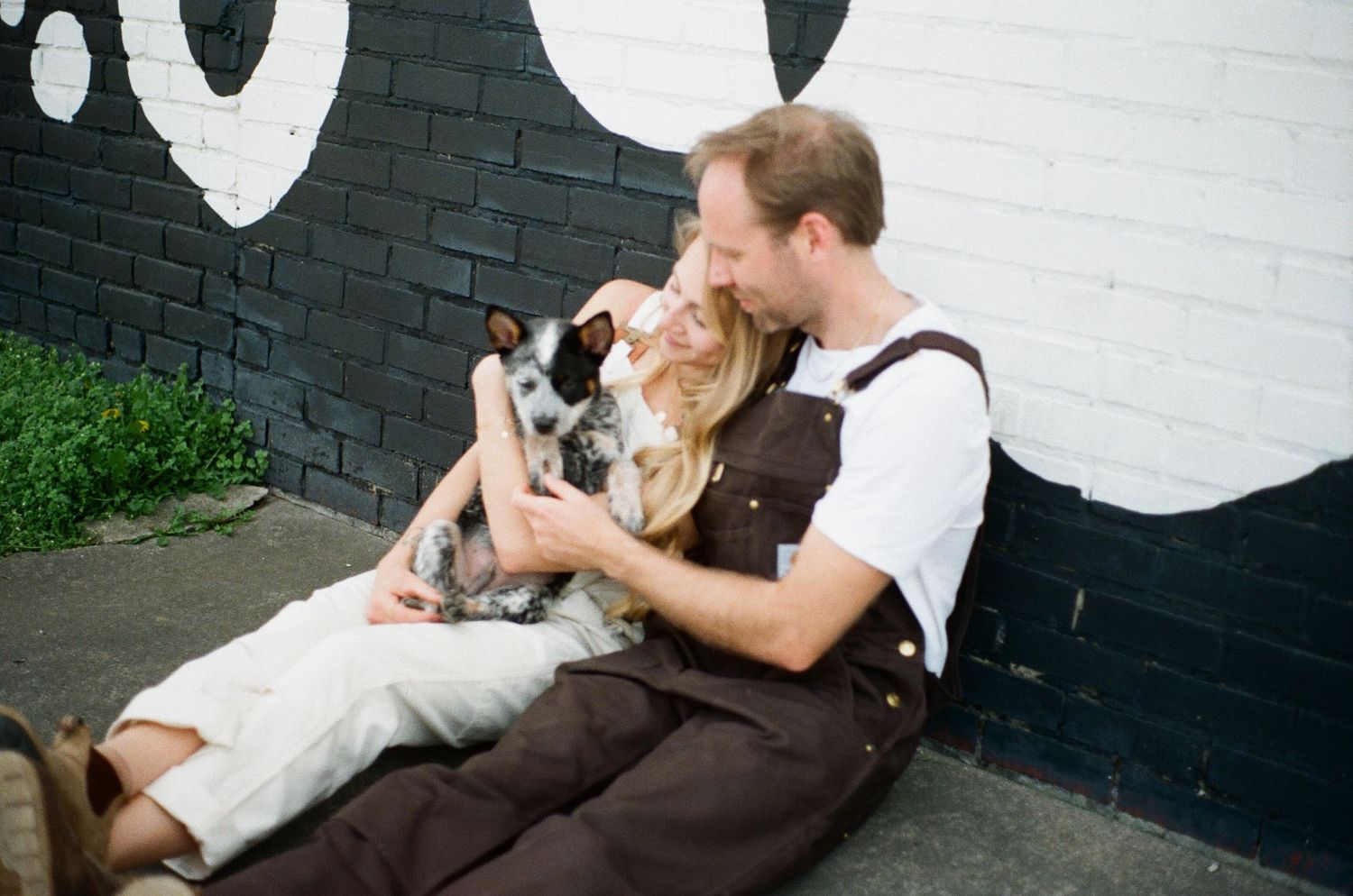 Person cuddling with their dog against a black and white painted wall.