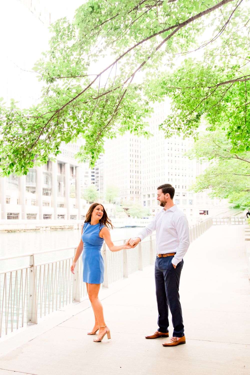 woman in blue dress twirling around with her fiance in white shirt for sunrise chicago engagement pictures