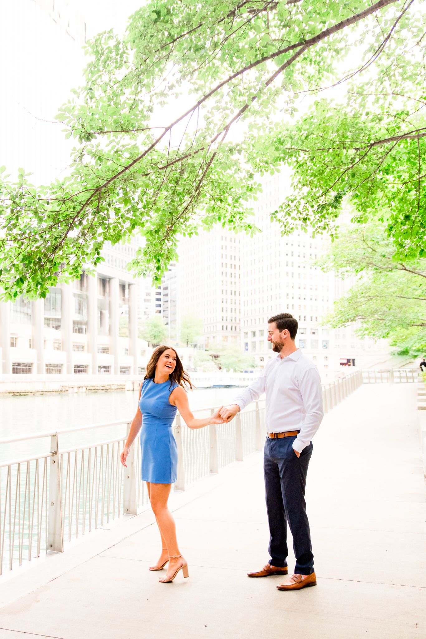 woman in blue dress twirling around with her fiance in white shirt for sunrise chicago engagement pictures