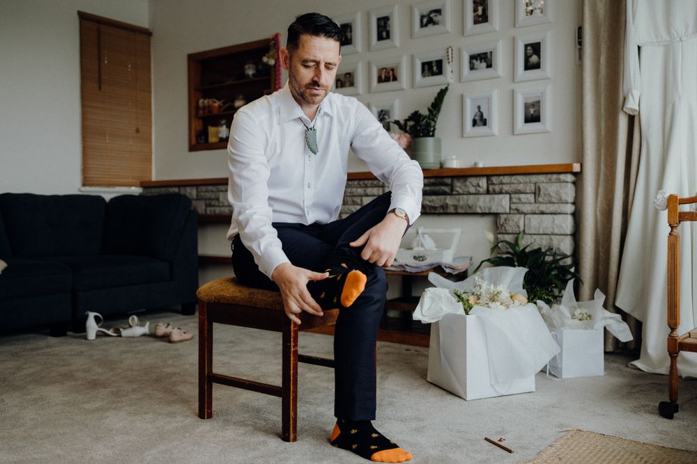 Getting ready scene showing a person in formal attire putting on orange socks.