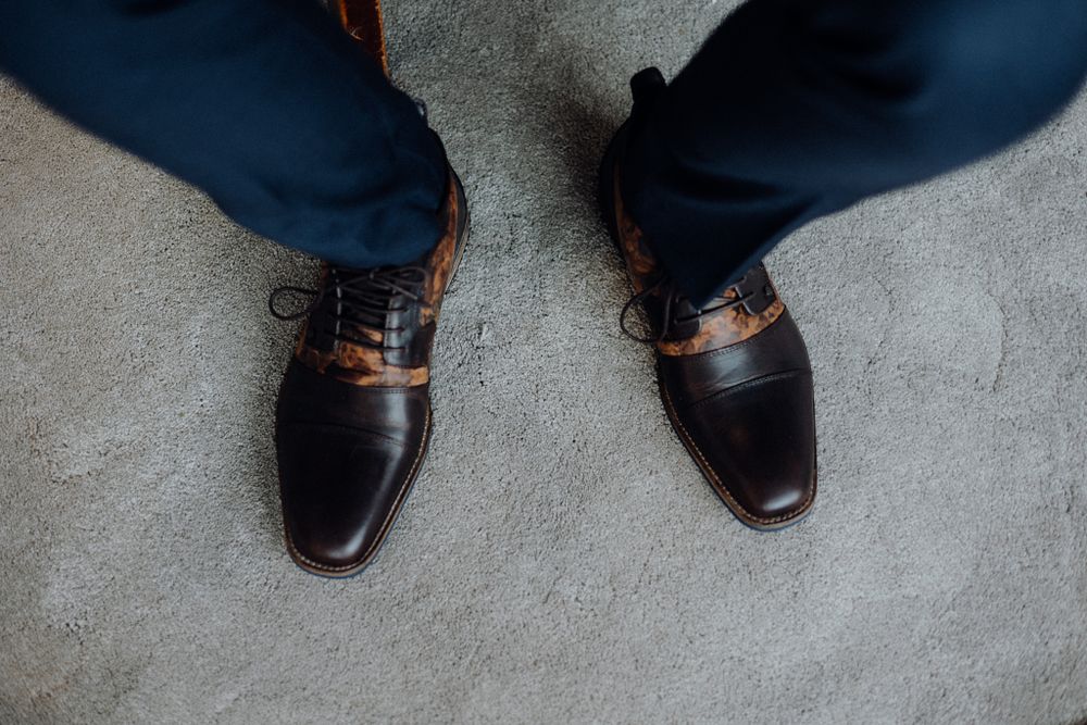 Close-up of polished two-tone brown and black leather dress shoes on carpet.