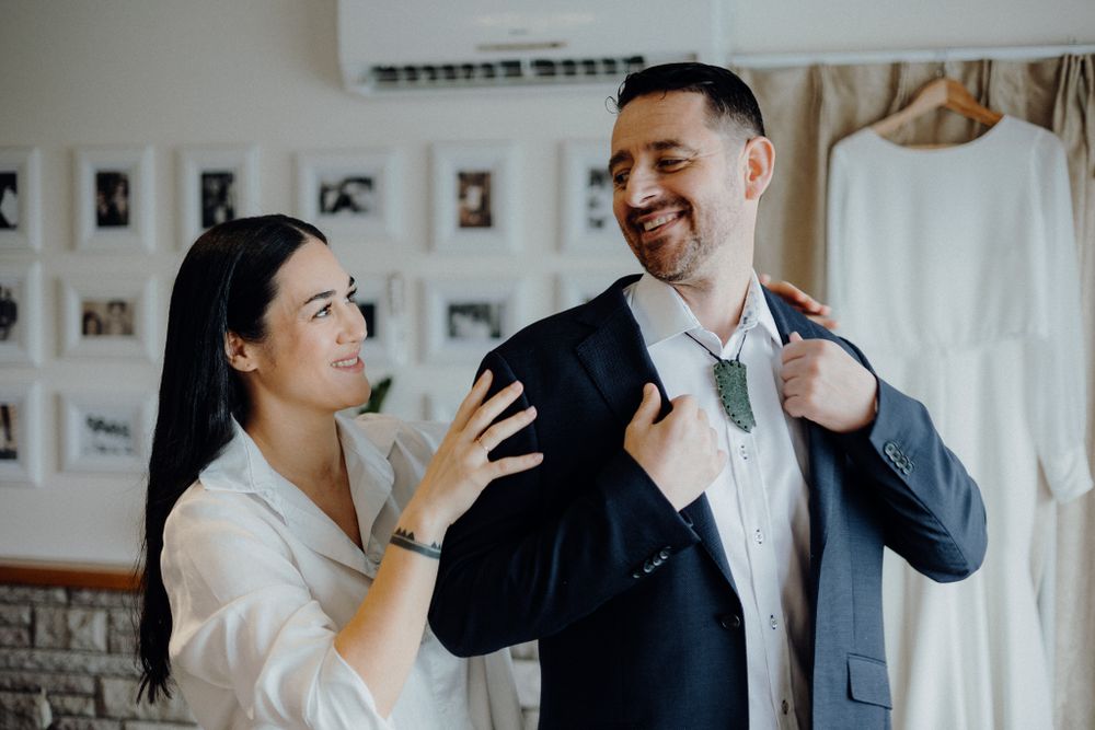 Candid pre-wedding moments showing final suit adjustments in getting ready room.