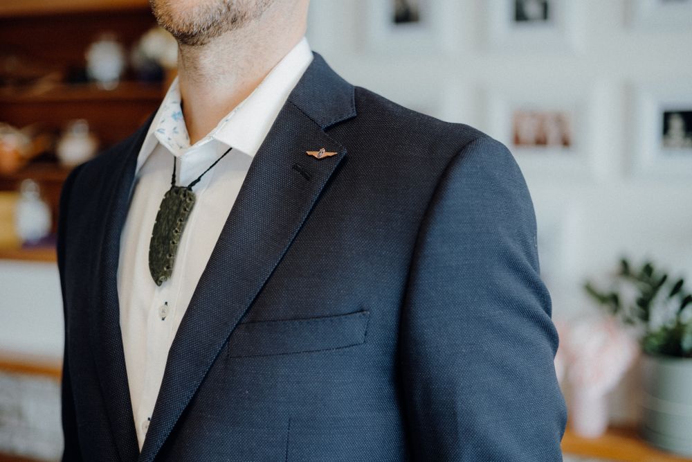 Detail shot of navy suit lapel with boutonniere pin and vest.