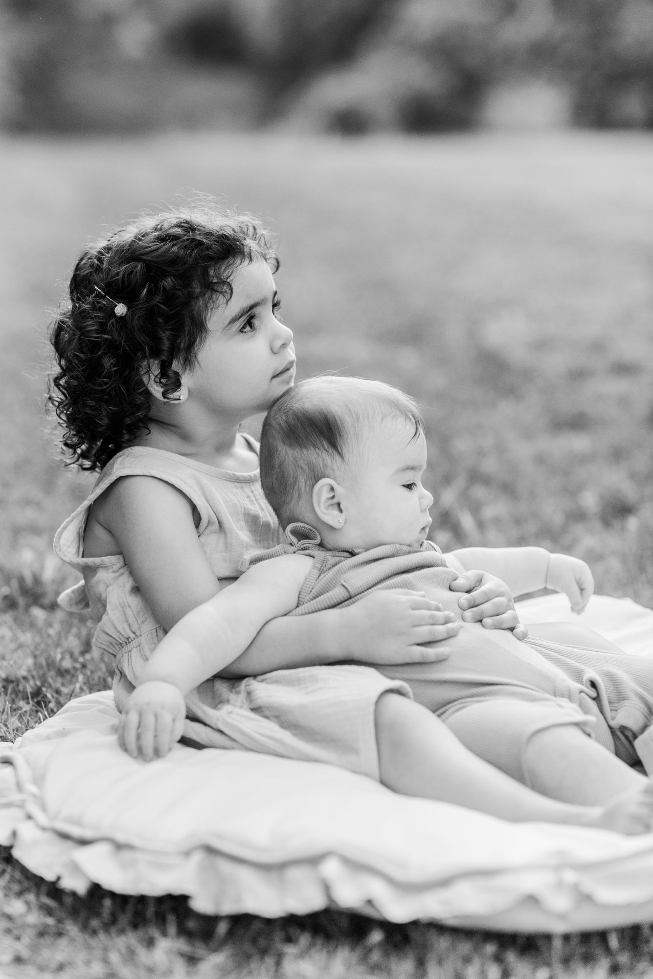 Young sisters sitting in the grass in black and white in Pittsburgh, Pennsylvania
