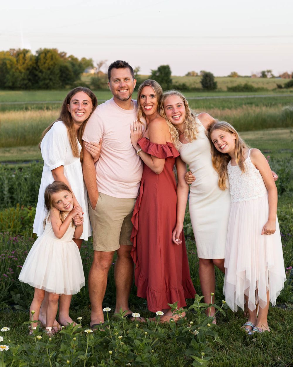 Family group photo in field wearing coordinating outfits during golden hour.