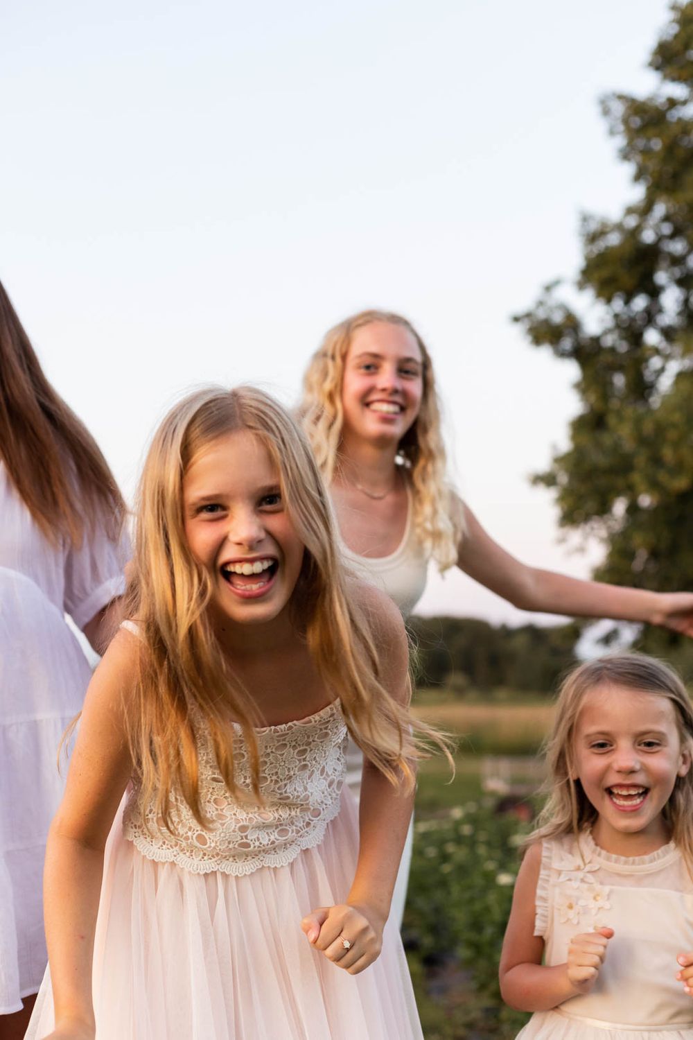 People laughing and enjoying a candid moment together outdoors in white dresses.