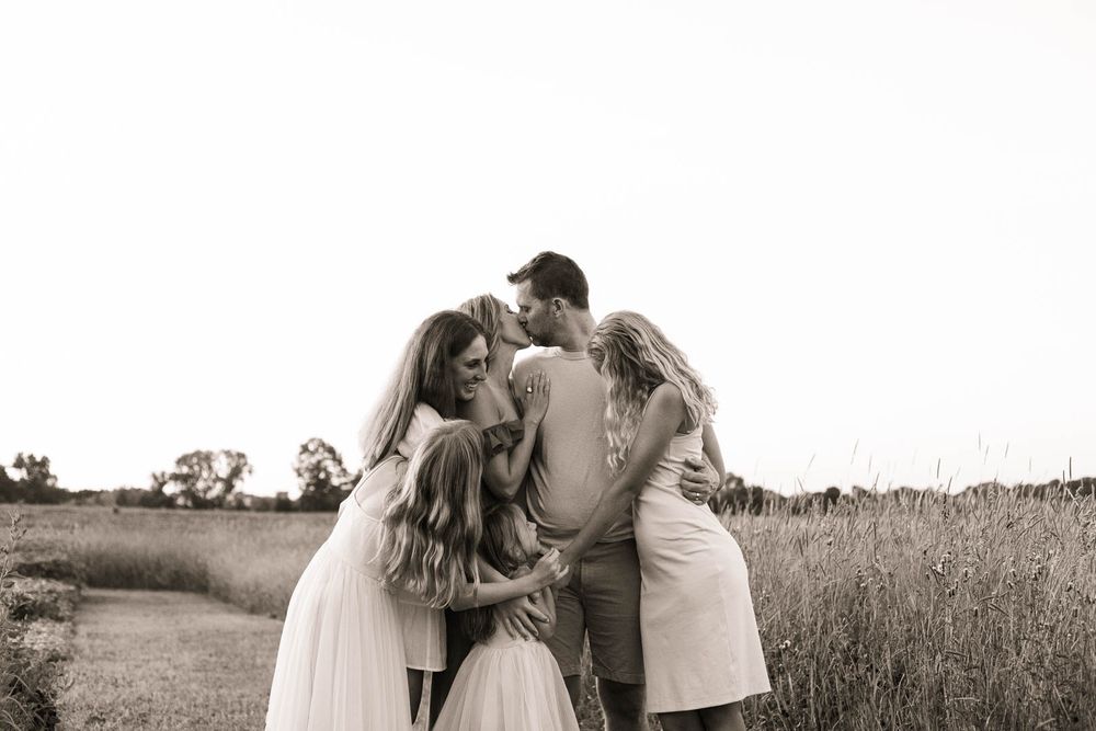A group hugs together in a field captured in black and white.
