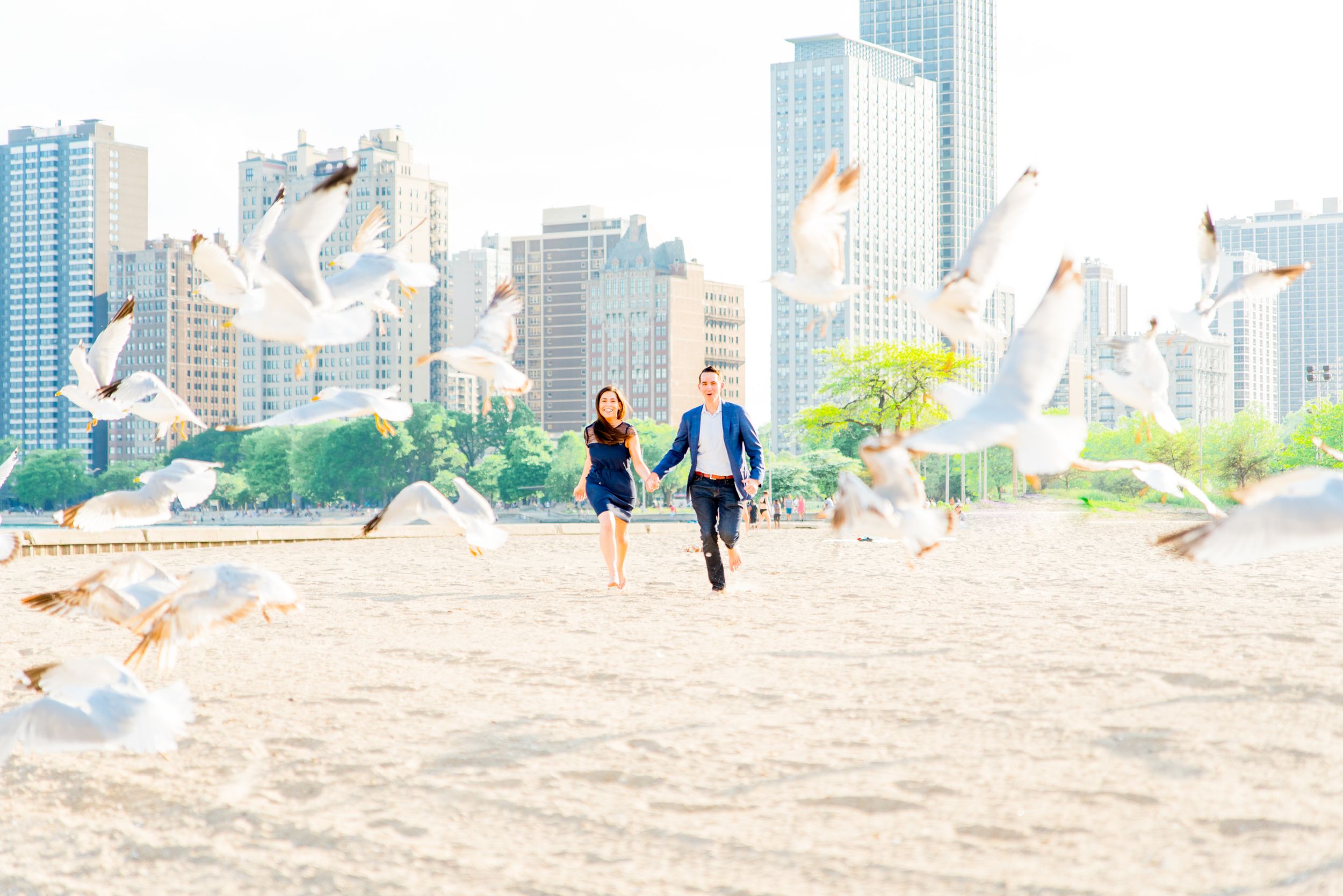 man and woman running through seagulls at North Avenue Beach proposal