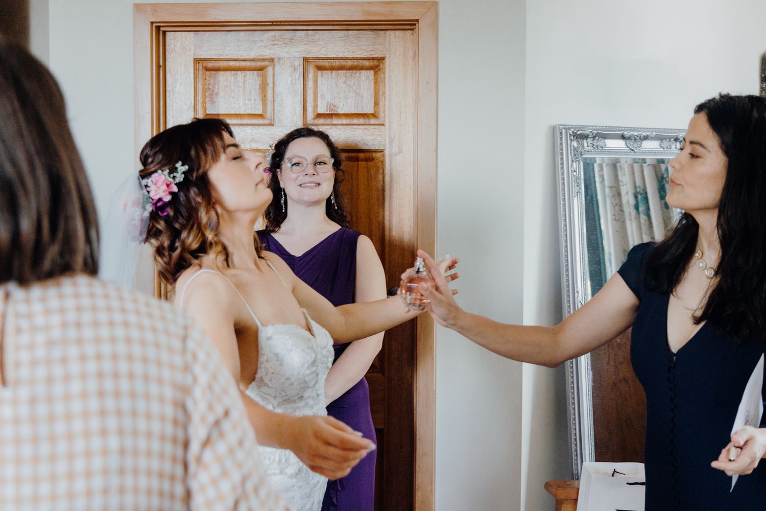 Wedding preparation scene with people in purple and black dresses gathered in conversation.