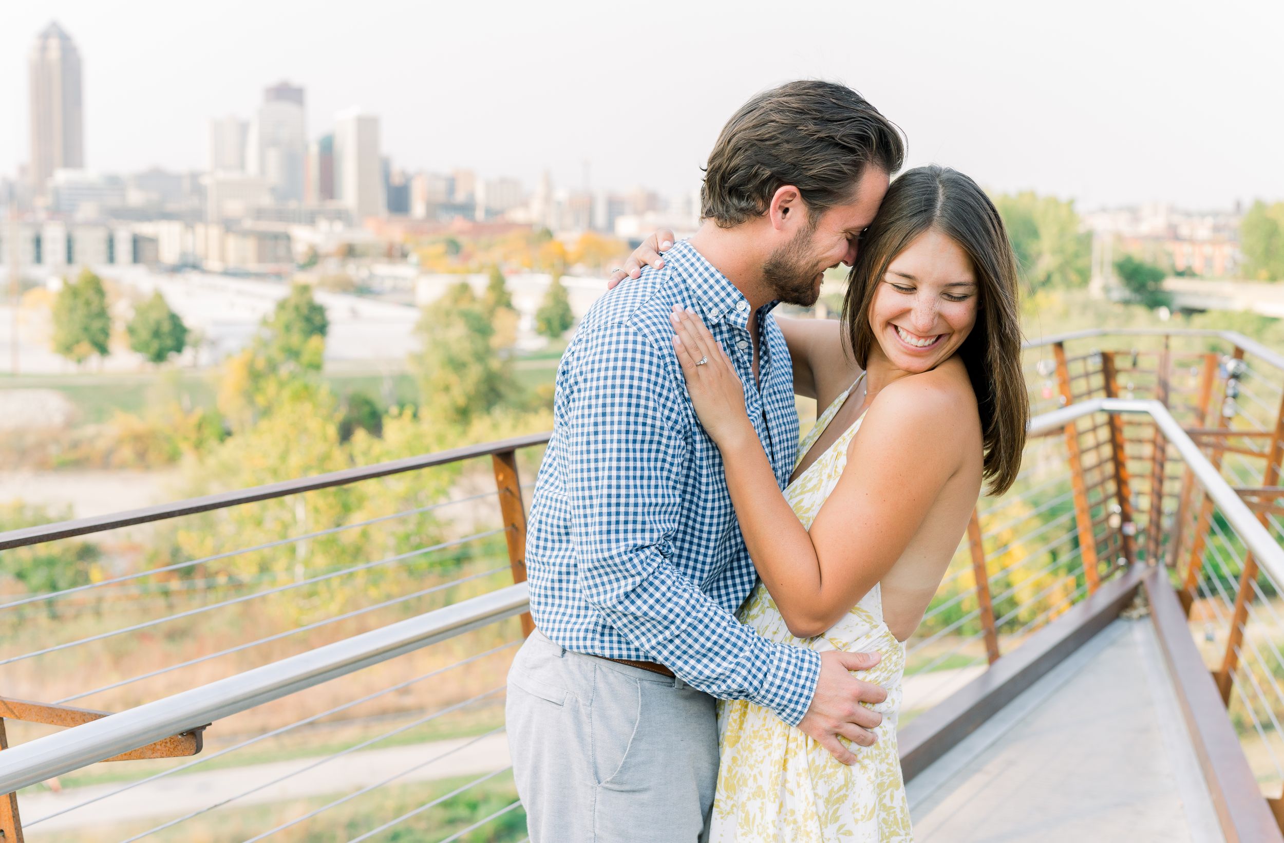 Des Moines Engagement photos with skyline of downtown Des Moines, Iowa with light and airy photographer Nicole Laing