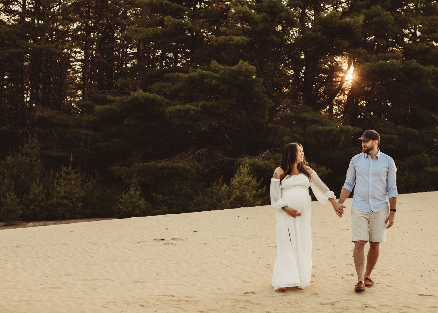 Professional photo of a pregnant mother dressed in white on the beach and her husband