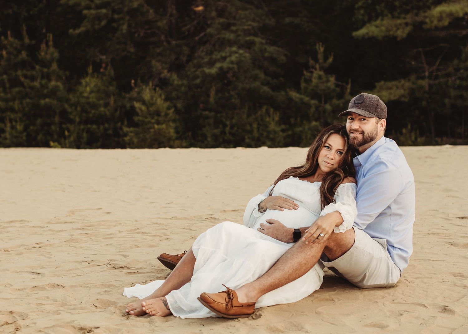 Professional photo of a pregnant mother dressed in white on the beach and her husband