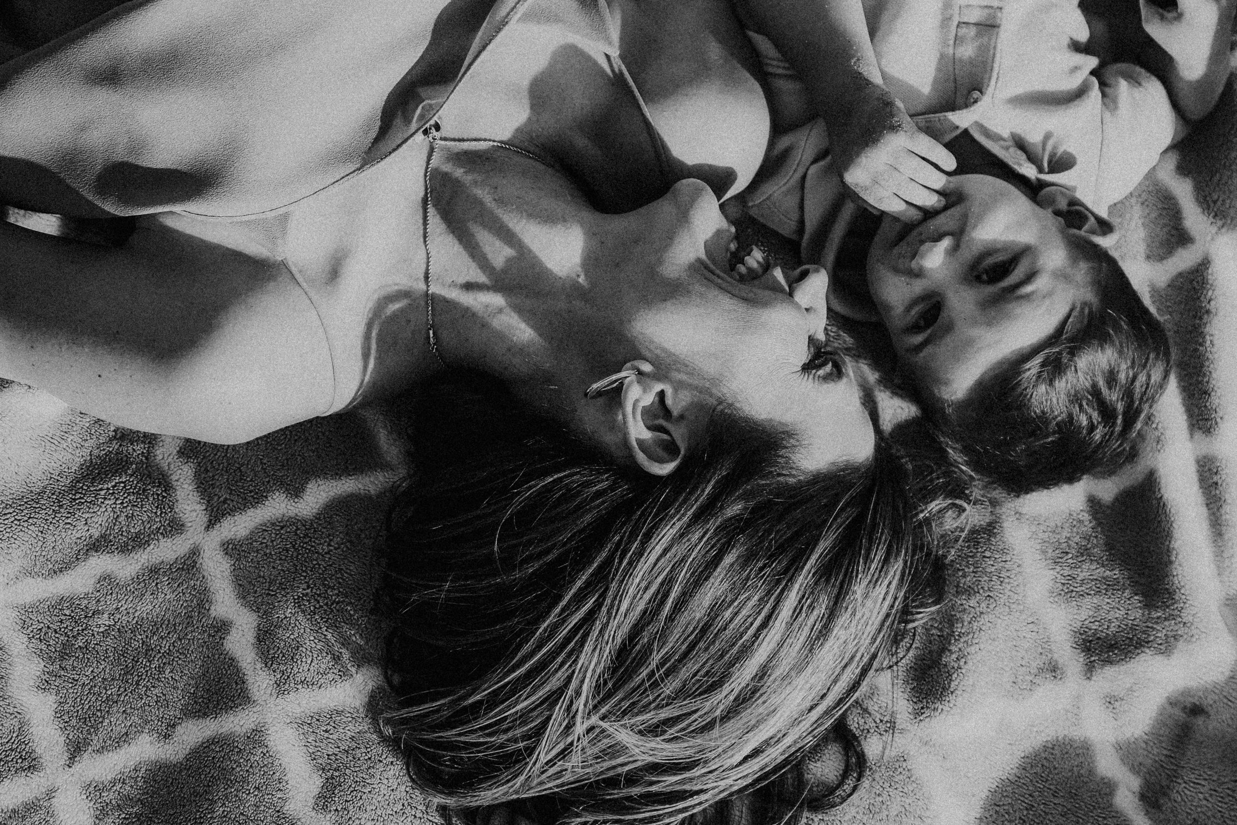 black and white photo of mother and son laughing while laying on a blanket
