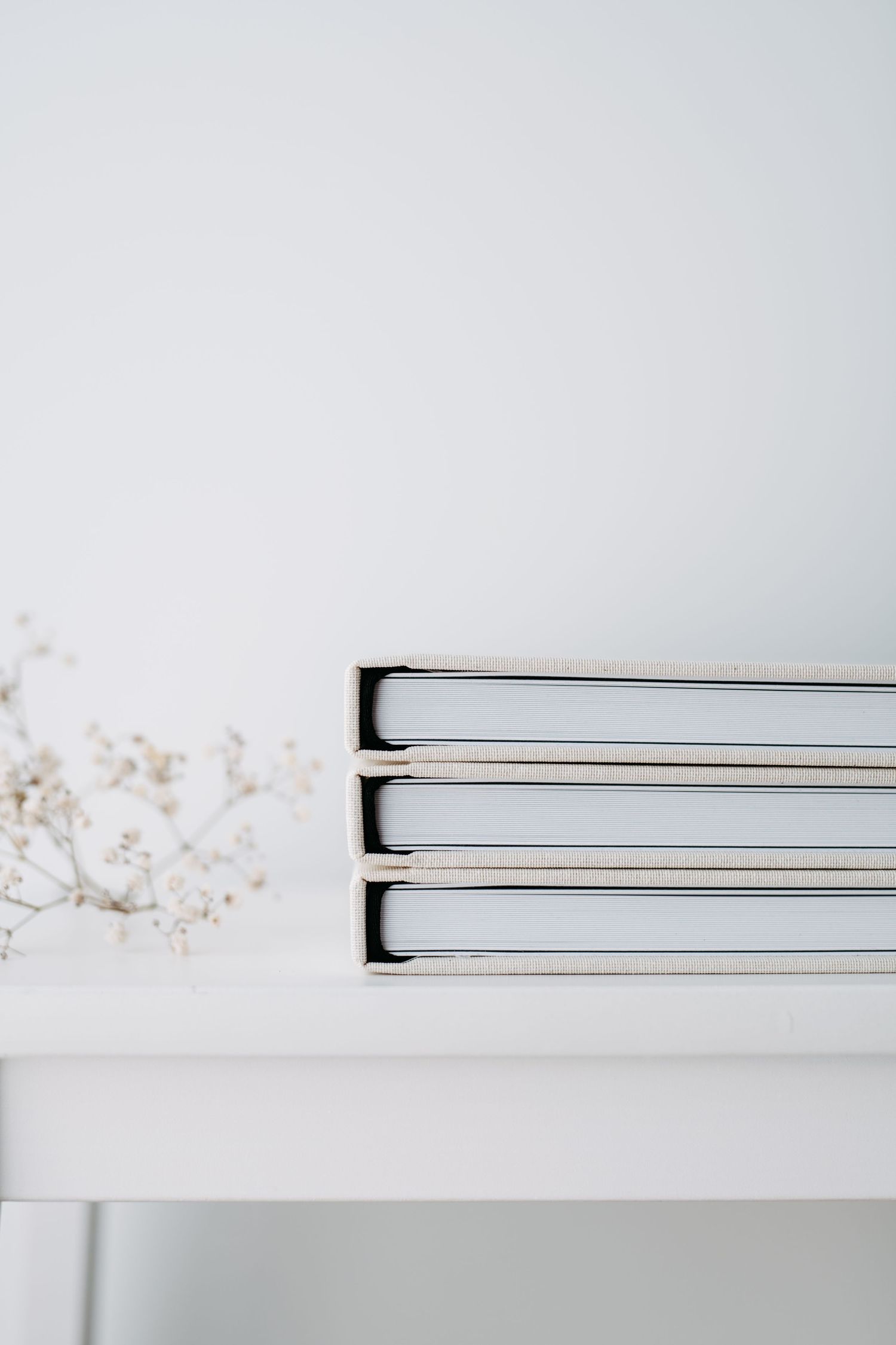 Three white photo albums stacked neatly on a white surface.