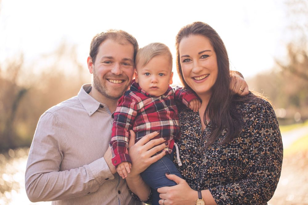 A mother and father embrace their little boy in Cassiobury Park by the canal - Family Photography
