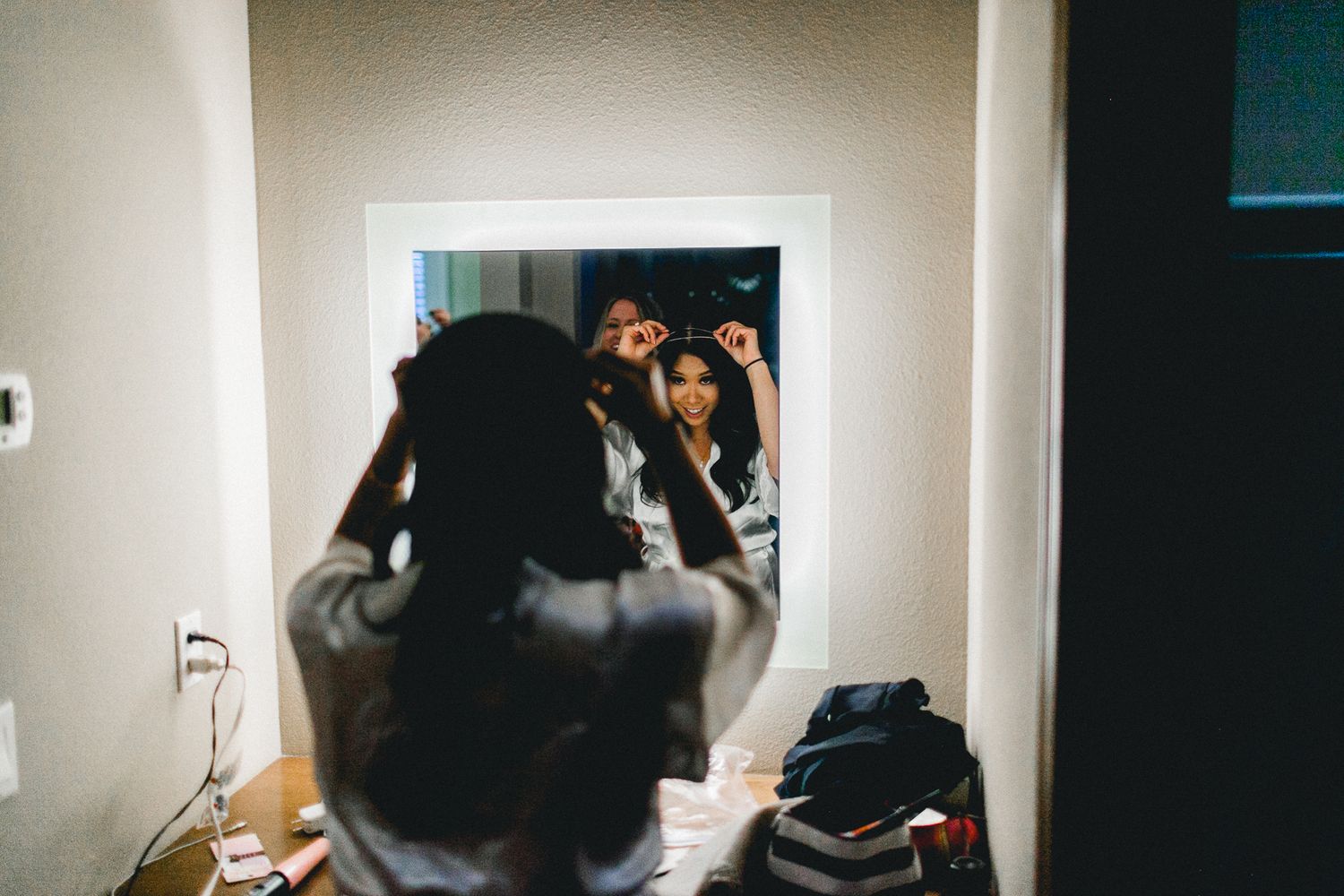 bride adjusting crown in front of mirror
