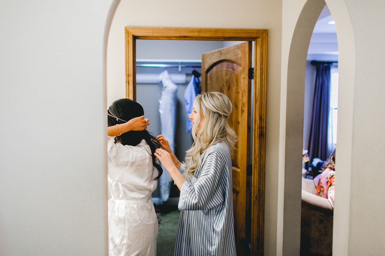 bridesmaid helping bride out during prep