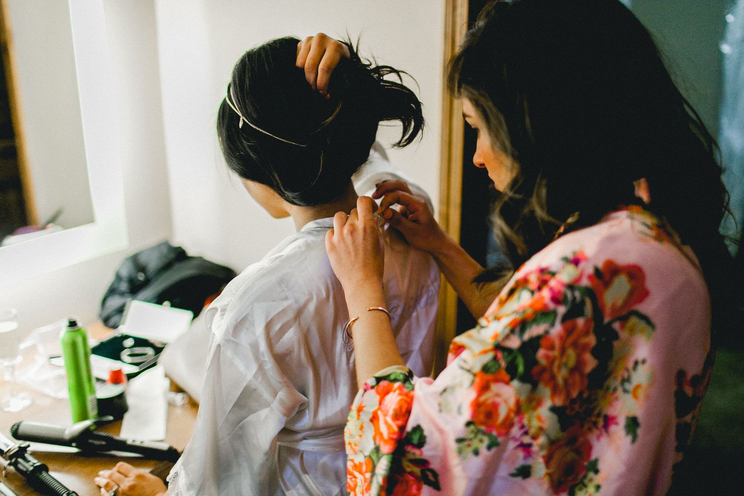 maid of honor helping bride put on necklace