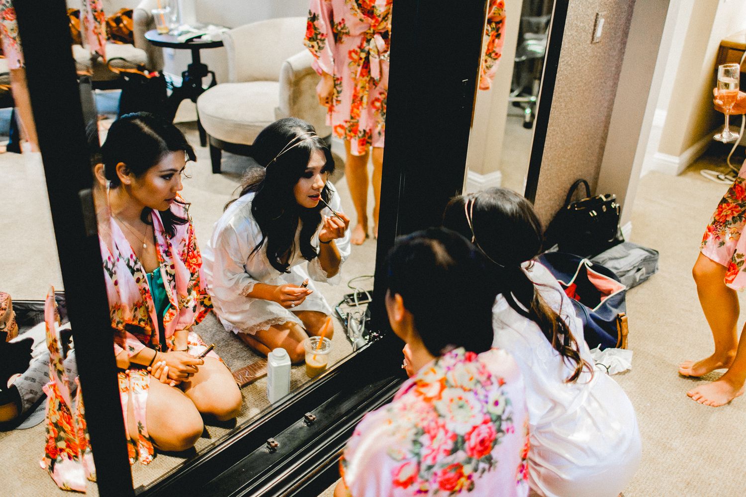 bride and bridesmaid adjusting makeup in front of mirror
