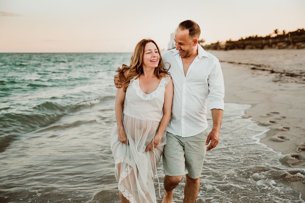 couple laughing and walking on the beach