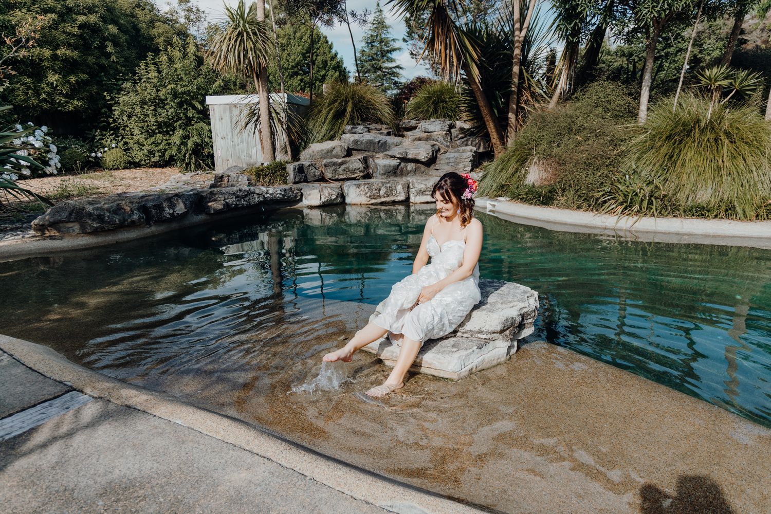 A beautiful poolside scene with a white dress by a rock-lined swimming pool.