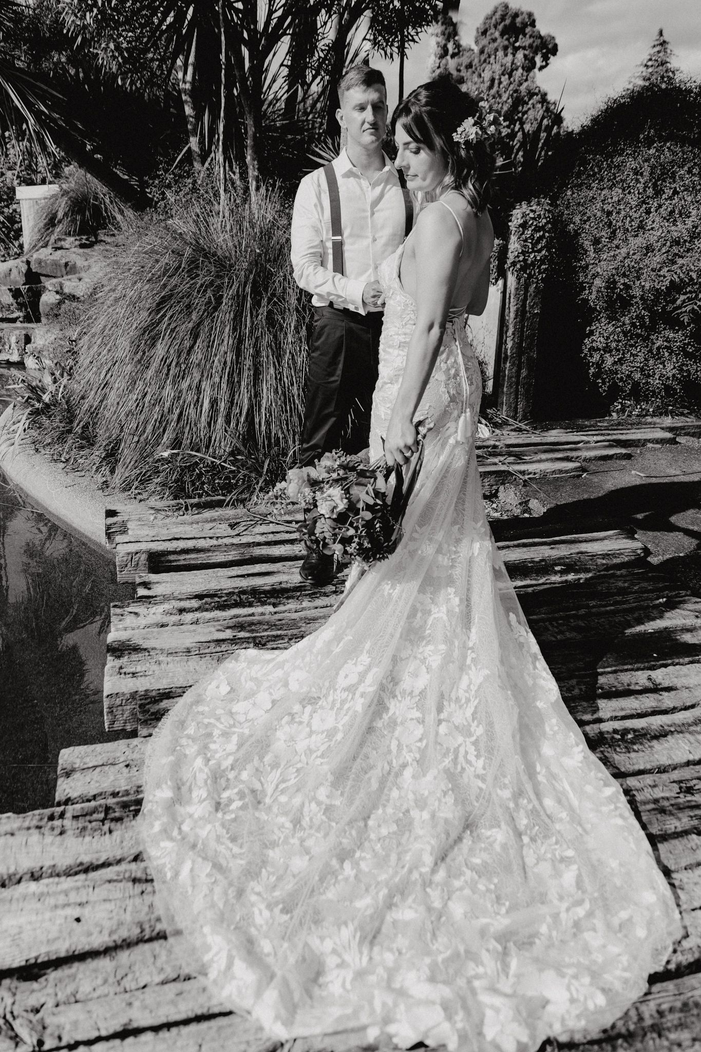 A black and white portrait showcasing a stunning lace wedding gown with a dramatic cathedral train.