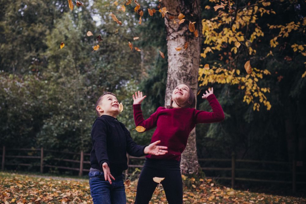 brother and sister throwing fall leaves in the air