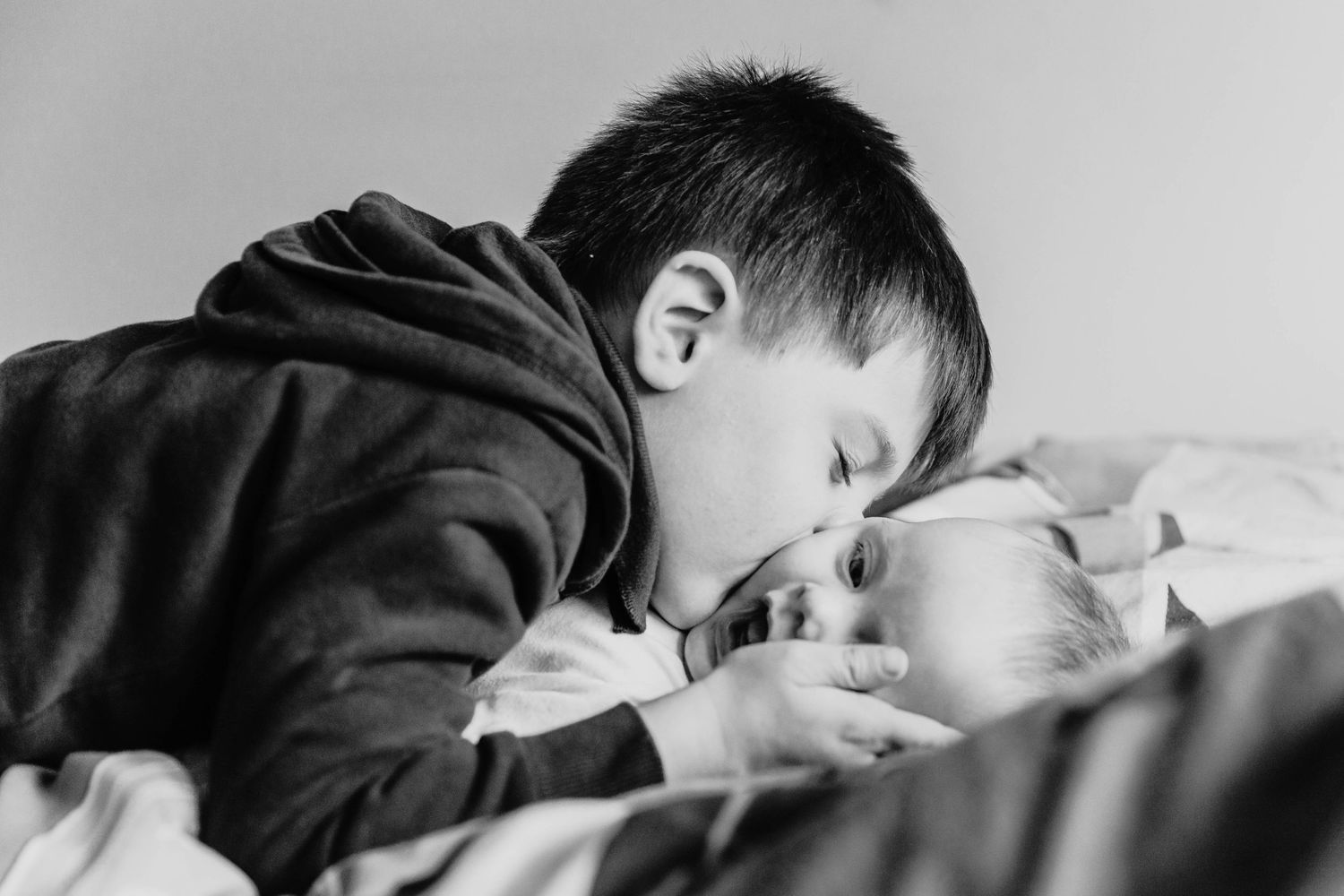 brother kissing baby sister on cheek